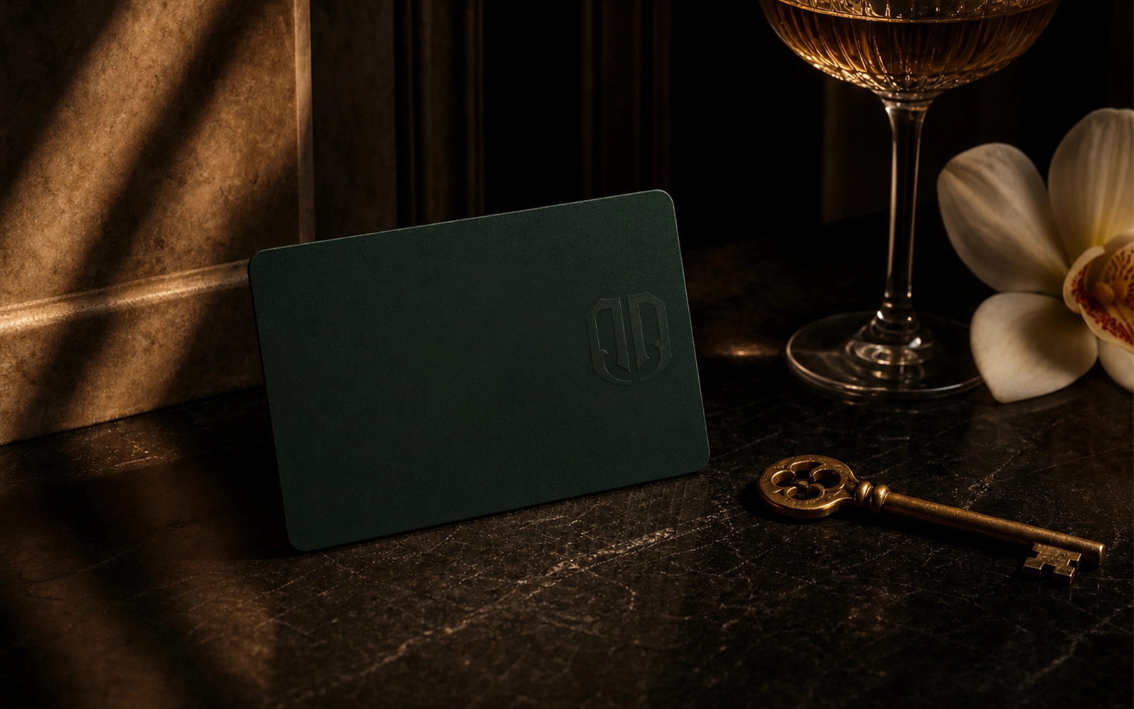 Blank burgundy membership card, brass key, orchid, and coupe glass